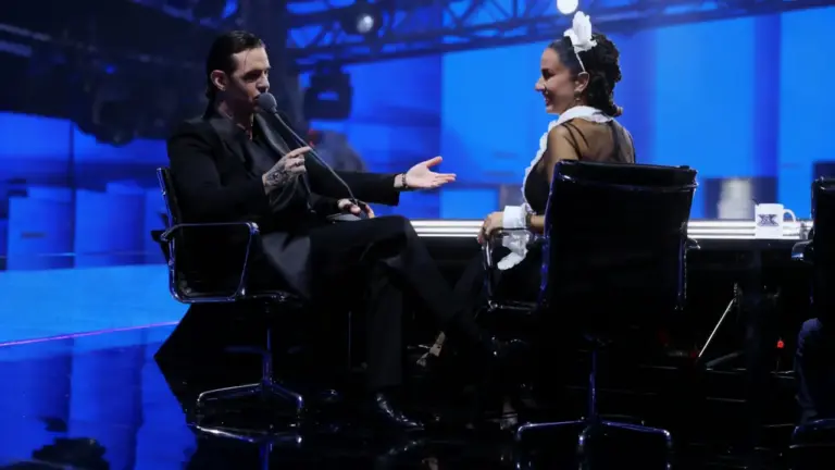 Due persone sedute al tavolo dei giudici durante il primo live di X Factor