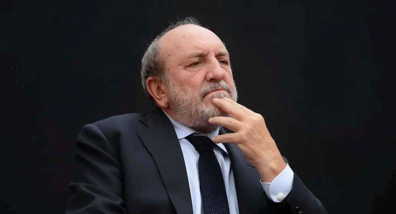 Uomo anziano in abito scuro con espressione pensierosa su sfondo nero