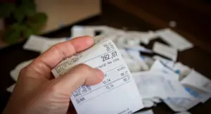 Persona che tiene in mano uno scontrino con altri scontrini sullo sfondo