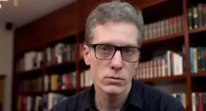 Una persona con occhiali in un ambiente con scaffali pieni di libri