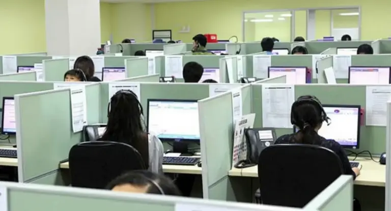 Operatori al lavoro in un call center con cuffie e computer
