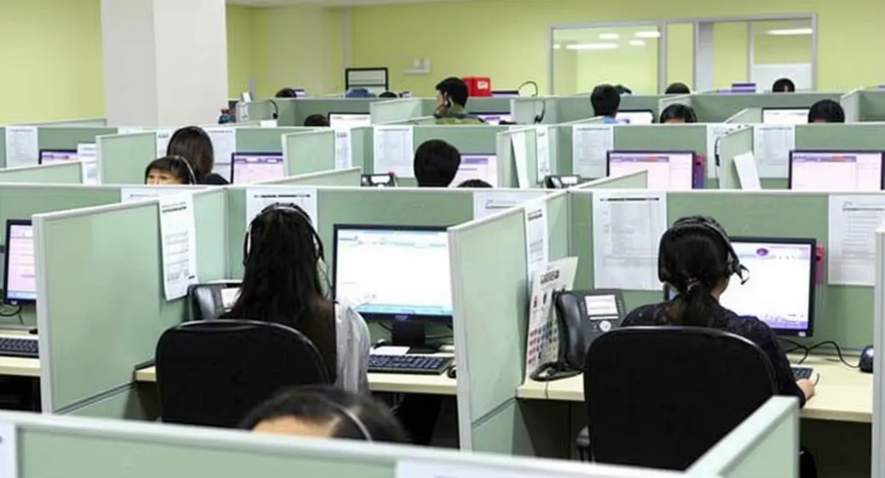 Operatori al lavoro in un call center con cuffie e computer