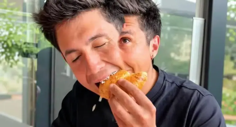 Una persona seduta al tavolo mentre addenta un cornetto in un locale moderno