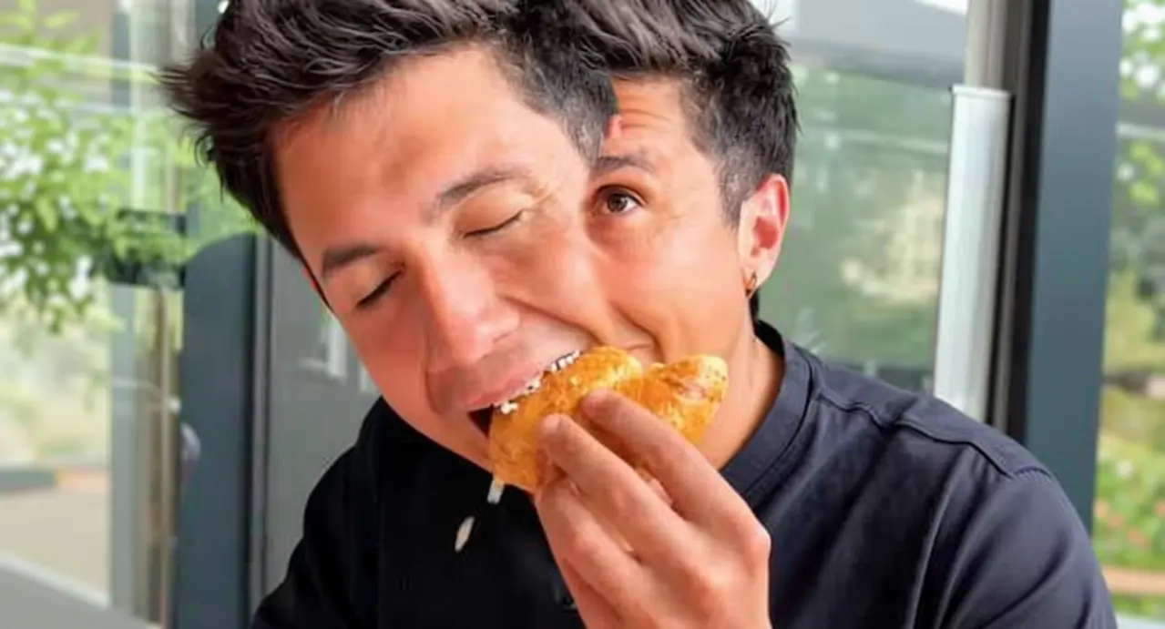 Una persona seduta al tavolo mentre addenta un cornetto in un locale moderno