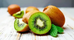 Kiwi freschi tagliati a metà su un tavolo con foglie di menta