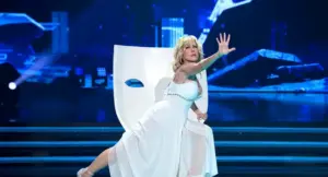 Una donna in abito bianco su un palco con scenografia futuristica