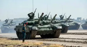 Carri armati in movimento durante una parata militare con un soldato in piedi davanti