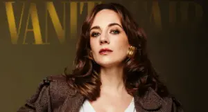 Una donna con capelli castani e orecchini dorati in posa davanti a uno sfondo scuro